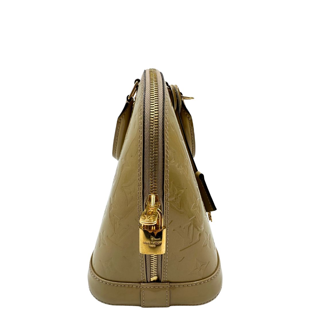 Vista laterale di una borsa Alma PM Louis Vuitton in pelle Vernis color noisette con parti metalliche dorate e doppi manici stondati; da portare a mano. Completa di lucchetto e chiavi.