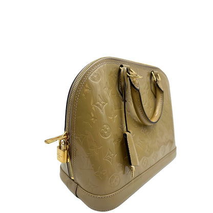Laterale sinistro di una borsa Alma PM Louis Vuitton in pelle Vernis color noisette con parti metalliche dorate e doppi manici stondati; da portare a mano. Completa di lucchetto e chiavi.