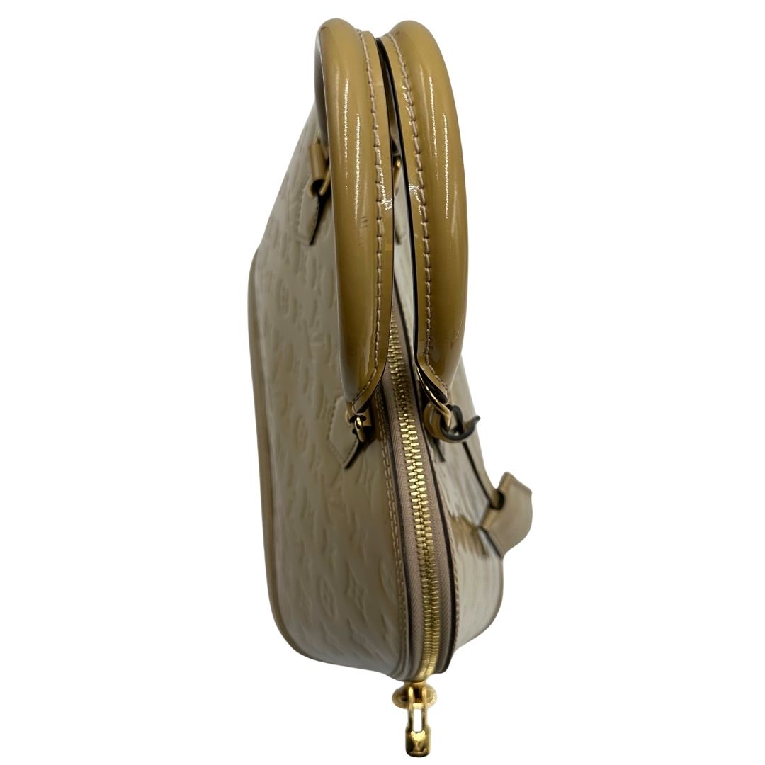 Manici di una borsa Alma PM Louis Vuitton in pelle Vernis color noisette con parti metalliche dorate e doppi manici stondati; da portare a mano. Completa di lucchetto e chiavi.