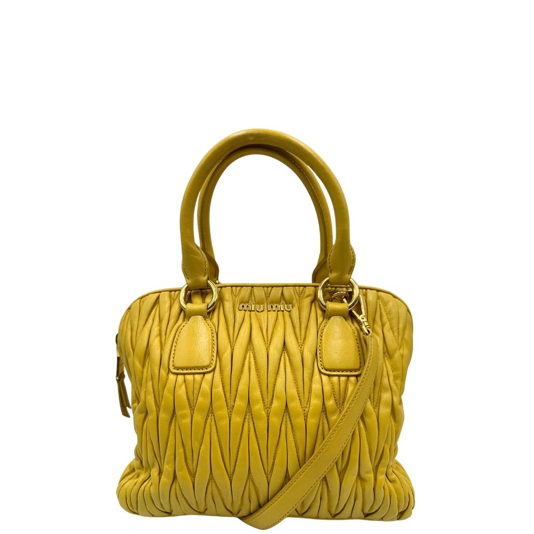 front Borsa Miu Miu realizzata in pelle matelassè gialla con parti metalliche dorate; munita di doppi manici stondati e una tracolla amovibile e regolabile. Completa di dustbag, di lusso, originale, usata.