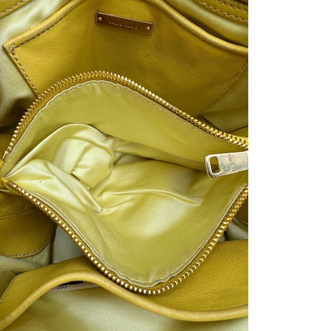 interno Borsa Miu Miu realizzata in pelle matelassè gialla con parti metalliche dorate; munita di doppi manici stondati e una tracolla amovibile e regolabile. Completa di dustbag, di lusso, originale, usata. 