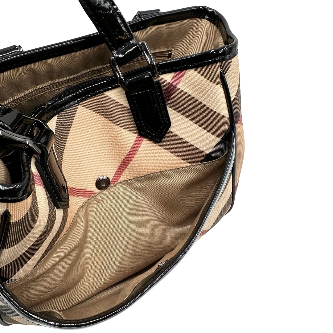 Interno di una borsa Burberry in canvas beige tartan con finiture in pelle nera lucida e parti metalliche effetto renio. Munita di doppi manici stondati. Completa di dustbag.