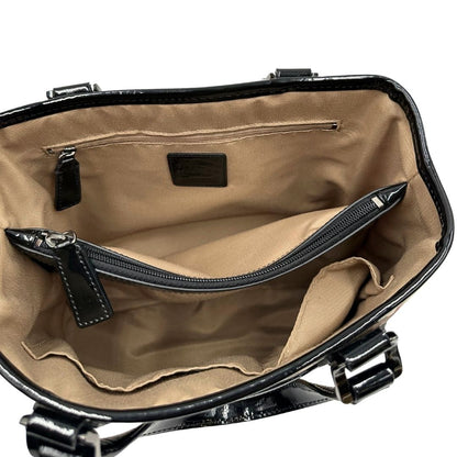 Interno di una borsa Burberry in canvas beige tartan con finiture in pelle nera lucida e parti metalliche effetto renio. Munita di doppi manici stondati. Completa di dustbag.