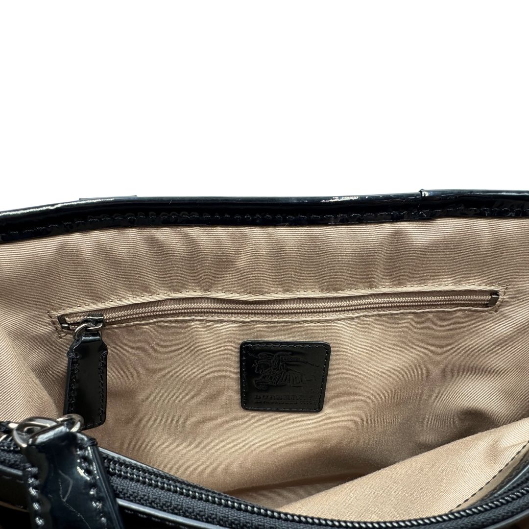 Interno di una borsa Burberry in canvas beige tartan con finiture in pelle nera lucida e parti metalliche effetto renio. Munita di doppi manici stondati. Completa di dustbag.