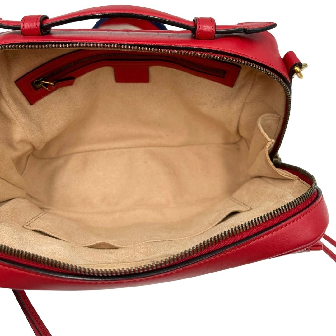 Interno di una borsa Gucci Marmont in pelle matelassè rossa e parti metalliche dorate; munita di un manico superiore e di una tracolla in tessuto web blu/bianco/rosso, regolabile ed amovibile. Indossabile a mano o a tracolla. Completa di dustbag.