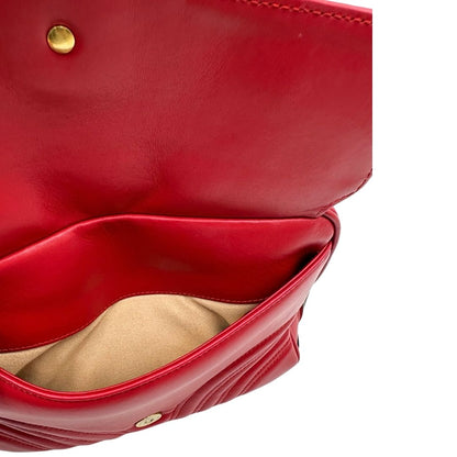 Interno di una borsa Gucci Marmont in pelle matelassè rossa e parti metalliche dorate; munita di un manico superiore e di una tracolla in tessuto web blu/bianco/rosso, regolabile ed amovibile. Indossabile a mano o a tracolla. Completa di dustbag.