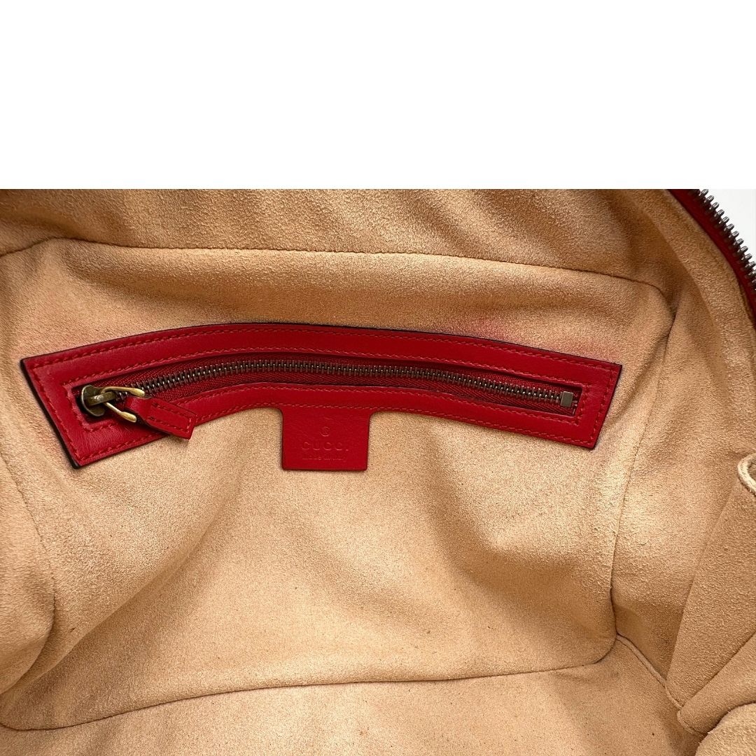 Interno di una borsa Gucci Marmont in pelle matelassè rossa e parti metalliche dorate; munita di un manico superiore e di una tracolla in tessuto web blu/bianco/rosso, regolabile ed amovibile. Indossabile a mano o a tracolla. Completa di dustbag.