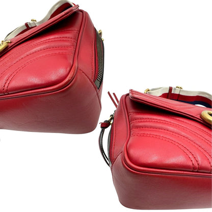 Angoli di una borsa Gucci Marmont in pelle matelassè rossa e parti metalliche dorate; munita di un manico superiore e di una tracolla in tessuto web blu/bianco/rosso, regolabile ed amovibile. Indossabile a mano o a tracolla. Completa di dustbag.