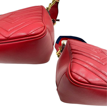 Angoli di una borsa Gucci Marmont in pelle matelassè rossa e parti metalliche dorate; munita di un manico superiore e di una tracolla in tessuto web blu/bianco/rosso, regolabile ed amovibile. Indossabile a mano o a tracolla. Completa di dustbag.
