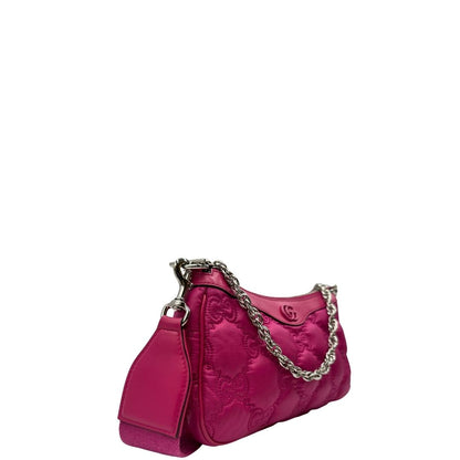 Laterale sinistro di una borsa Gucci in nylon trapuntato matelassé fucsia con trama GG, finiture in pelle tono su tono, manico singolo in catena e tracolla in tessuto regolabile ed amovibile. Rifinita con parti metalliche argentate. Completa di dustbag.