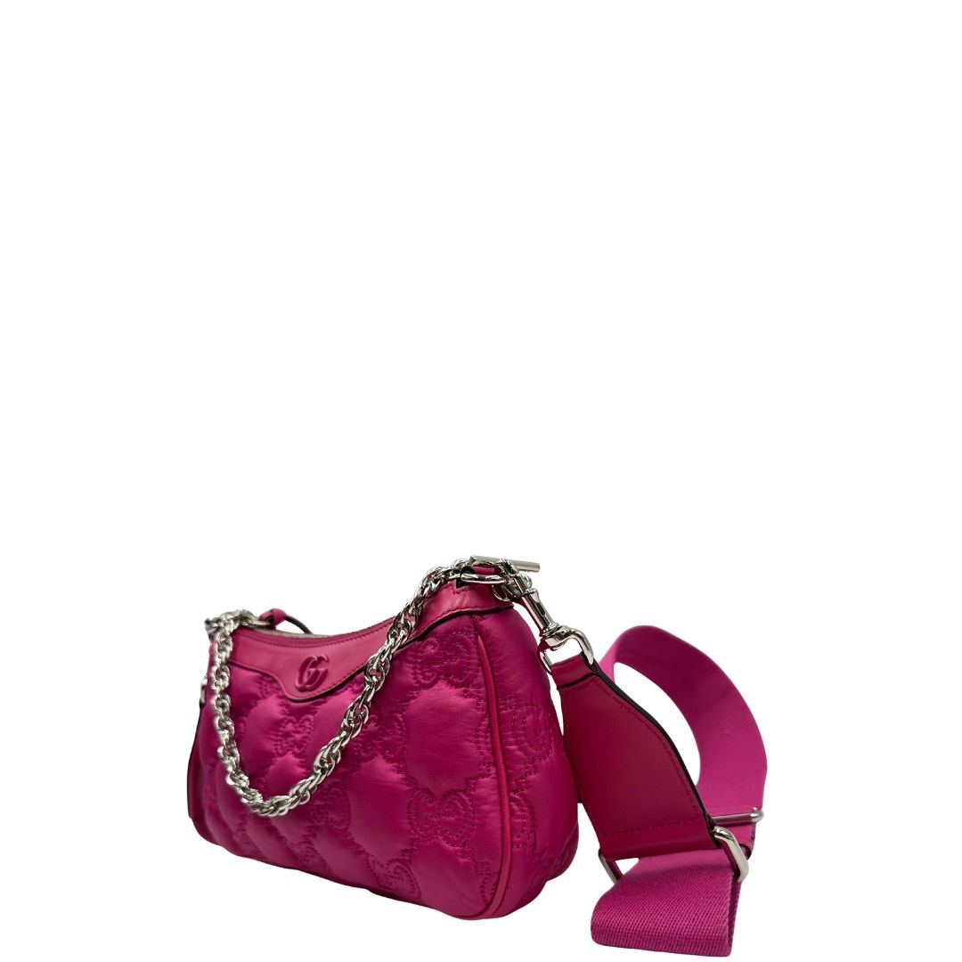 Laterale destro di una borsa Gucci in nylon trapuntato matelassé fucsia con trama GG, finiture in pelle tono su tono, manico singolo in catena e tracolla in tessuto regolabile ed amovibile. Rifinita con parti metalliche argentate. Completa di dustbag.