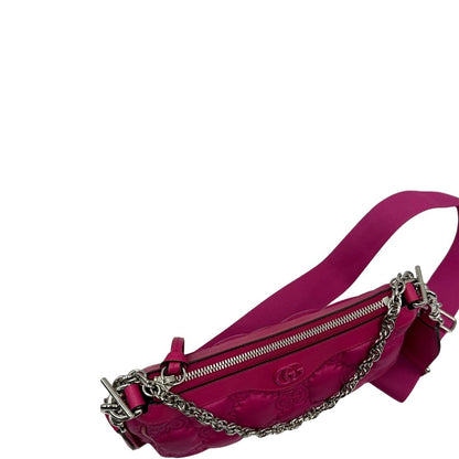 Vista superiore di una borsa Gucci in nylon trapuntato matelassé fucsia con trama GG, finiture in pelle tono su tono, manico singolo in catena e tracolla in tessuto regolabile ed amovibile. Rifinita con parti metalliche argentate. Completa di dustbag.