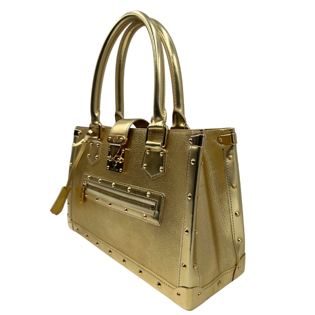 Laterale destro di una borsa Louis Vuitton Suhali Le Fabuleux in pelle color oro con parti metalliche dorate. Munita di doppi manici stondati, impreziosita da una clochette porta chiavi. Completa di scatola e dustbag.