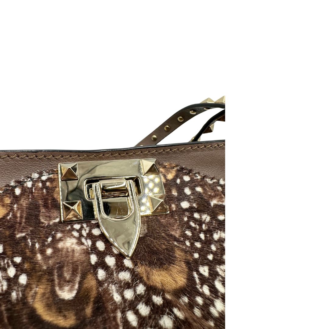 Chiusura di una Borsa Prada effetto cavallino stampato con piume multicolore e finiture in pelle marrone, con parti metalliche dorate; impreziosita da borchie piramidali e munita di doppi manici e tracolla amovibile. Completa di dustbag. Originale, usata, di lusso, in ottime condizioni.