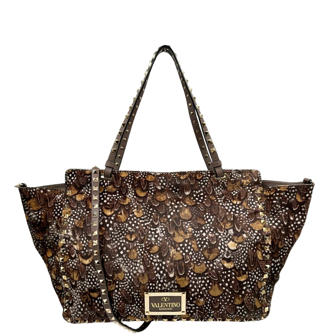 Retro di una Borsa Prada effetto cavallino stampato con piume multicolore e finiture in pelle marrone, con parti metalliche dorate; impreziosita da borchie piramidali e munita di doppi manici e tracolla amovibile. Completa di dustbag. Originale, usata, di lusso, in ottime condizioni.