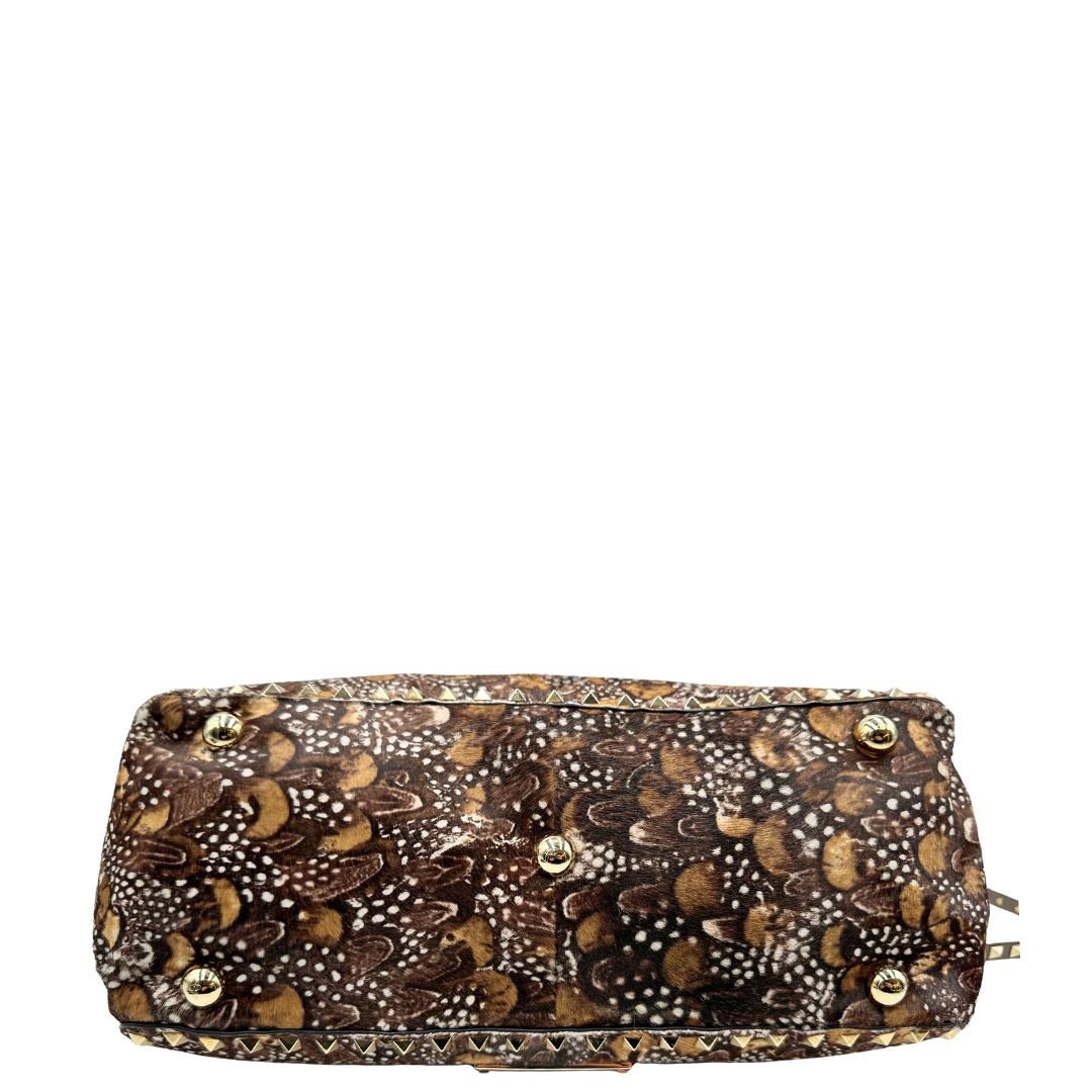 Base di una Borsa Prada effetto cavallino stampato con piume multicolore e finiture in pelle marrone, con parti metalliche dorate; impreziosita da borchie piramidali e munita di doppi manici e tracolla amovibile. Completa di dustbag. Originale, usata, di lusso, in ottime condizioni.