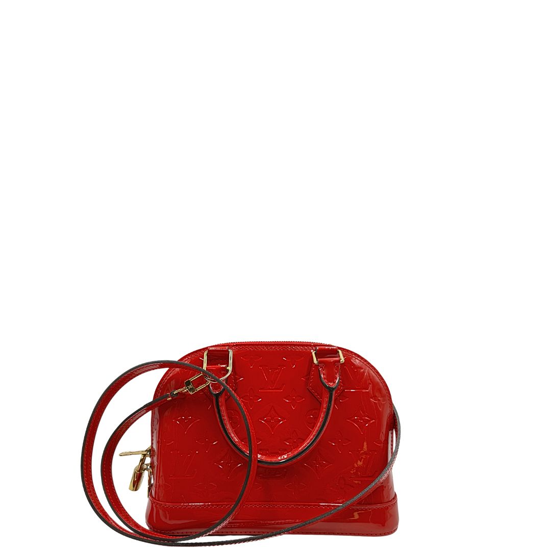 Retro di una borsa Louis Vuitton Alma BB in pelle vernis rossa con trama monogram empreinte e parti metalliche dorate. Munita di doppi manici stondati e tracolla amovibile, dotata di clochette porta chiavi. Completa di scatola, dustbag, lucchetto e chiavi.