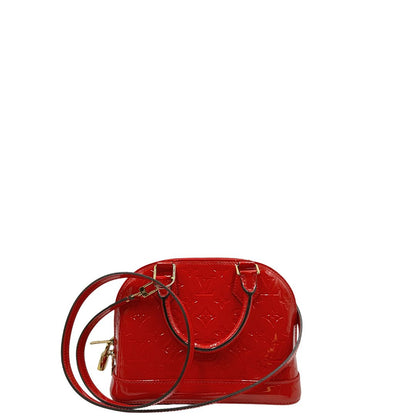 Retro di una borsa Louis Vuitton Alma BB in pelle vernis rossa con trama monogram empreinte e parti metalliche dorate. Munita di doppi manici stondati e tracolla amovibile, dotata di clochette porta chiavi. Completa di scatola, dustbag, lucchetto e chiavi.
