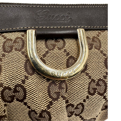 Dettaglio metallico di una pochette Gucci in tessuto Gucci in tessuto GG beige con finiture in pelle marrone e parti metalliche dorate; munita di un polsino, da portare a mano. Completa di dustbag.