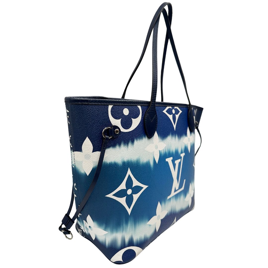 Laterale sinistro di una borsa Louis Vuitton Neverfull MM in canvas base tie-dye nelle tonalità del blu e bianco, con finiture in pelle blu navy. Da un lato ha stampa Monogram Giant, dall'altra Monogram. Parti metalliche argentate; munita di doppi manici e dustbag, indossabile a spalla.