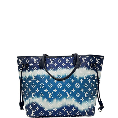 Retro di una borsa Louis Vuitton Neverfull MM in canvas base tie-dye nelle tonalità del blu e bianco, con finiture in pelle blu navy. Da un lato ha stampa Monogram Giant, dall'altra Monogram. Parti metalliche argentate; munita di doppi manici e dustbag, indossabile a spalla.