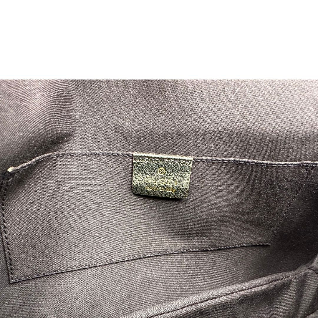 Interno di una borsa Gucci in pelle color oro anticato, dettaglio gioiello circolare sulla patta di chiusura composto da due teste di drago contrapposte, smaltate e decorate con micro strass, parti metalliche dorate; munita di doppi manici in catena a maglie. Indossabile a spalla.