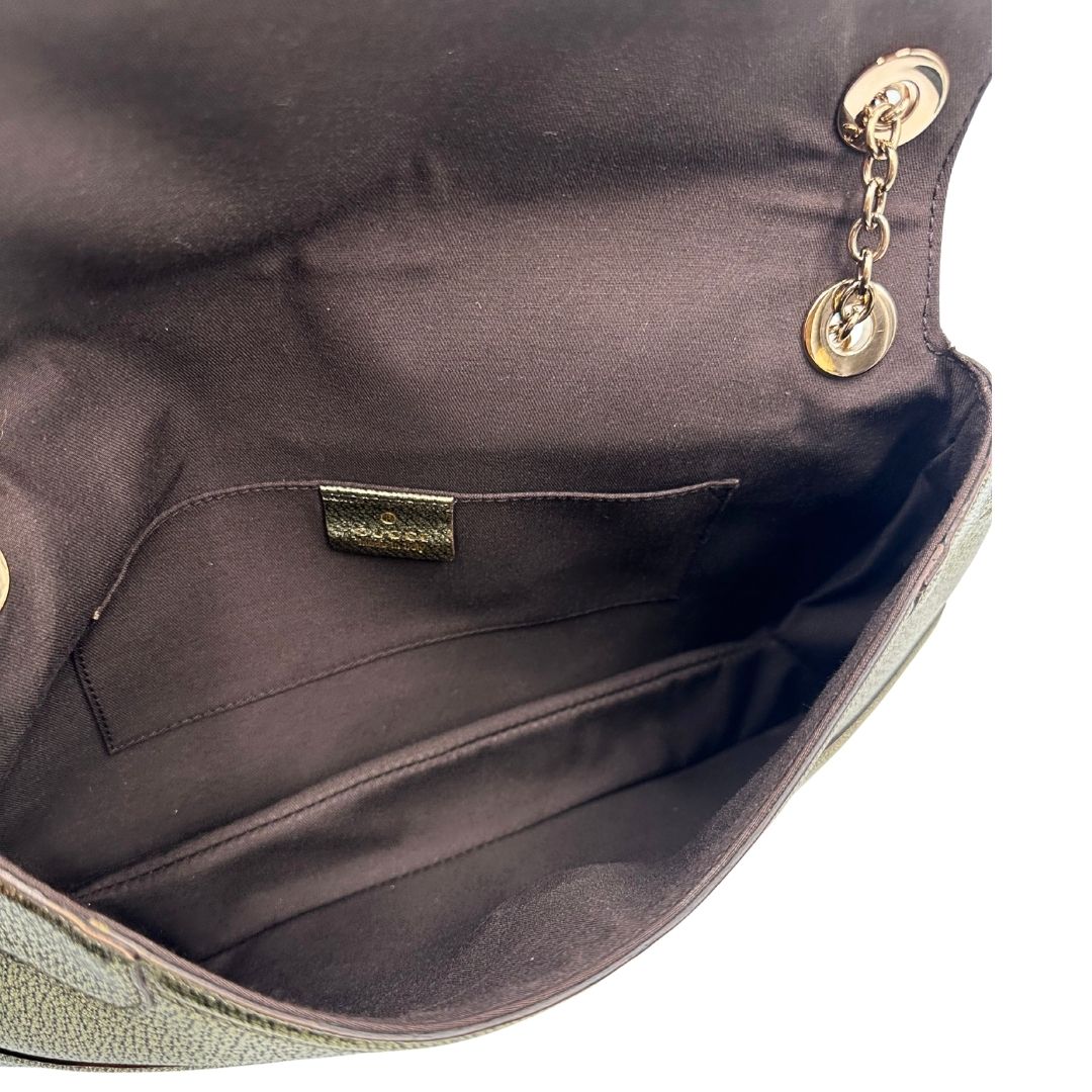 Interno di una borsa Gucci in pelle color oro anticato, dettaglio gioiello circolare sulla patta di chiusura composto da due teste di drago contrapposte, smaltate e decorate con micro strass, parti metalliche dorate; munita di doppi manici in catena a maglie. Indossabile a spalla.