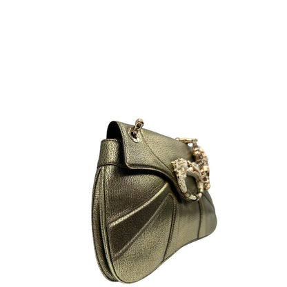 Laterale sinistro di una borsa Gucci in pelle color oro anticato, dettaglio gioiello circolare sulla patta di chiusura composto da due teste di drago contrapposte, smaltate e decorate con micro strass, parti metalliche dorate; munita di doppi manici in catena a maglie. Indossabile a spalla.