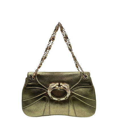 Front di una borsa Gucci in pelle color oro anticato, dettaglio gioiello circolare sulla patta di chiusura composto da due teste di drago contrapposte, smaltate e decorate con micro strass, parti metalliche dorate; munita di doppi manici in catena a maglie. Indossabile a spalla.