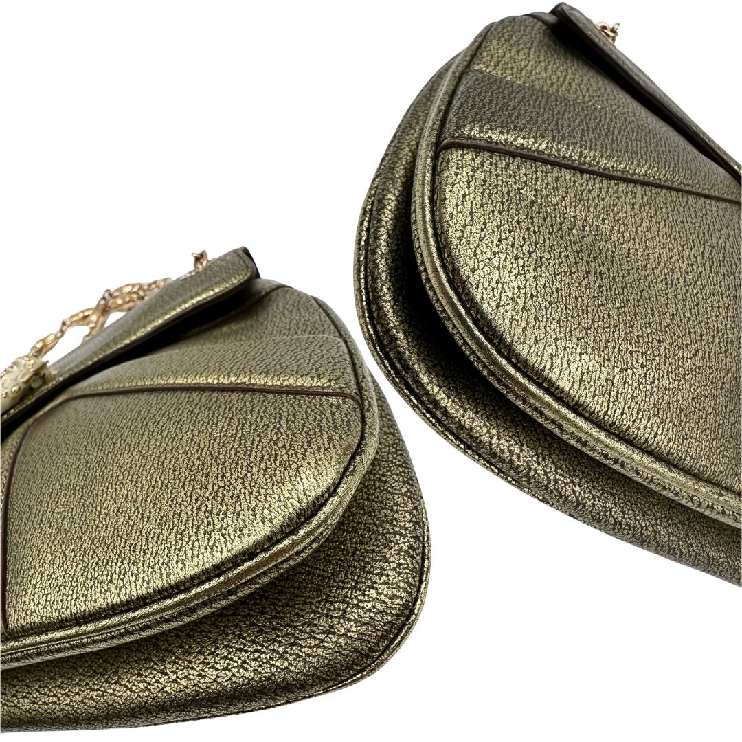 Angoli di una borsa Gucci in pelle color oro anticato, dettaglio gioiello circolare sulla patta di chiusura composto da due teste di drago contrapposte, smaltate e decorate con micro strass, parti metalliche dorate; munita di doppi manici in catena a maglie. Indossabile a spalla.