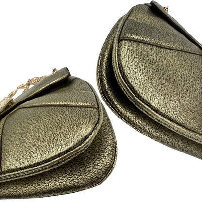 Angoli di una borsa Gucci in pelle color oro anticato, dettaglio gioiello circolare sulla patta di chiusura composto da due teste di drago contrapposte, smaltate e decorate con micro strass, parti metalliche dorate; munita di doppi manici in catena a maglie. Indossabile a spalla.