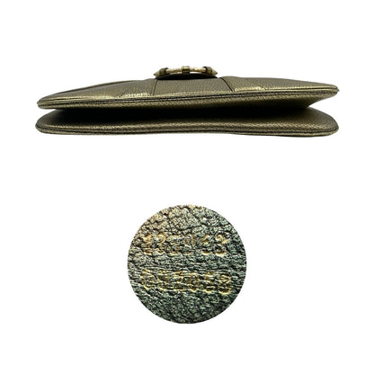 Base e codice di una borsa Gucci in pelle color oro anticato, dettaglio gioiello circolare sulla patta di chiusura composto da due teste di drago contrapposte, smaltate e decorate con micro strass, parti metalliche dorate; munita di doppi manici in catena a maglie. Indossabile a spalla.