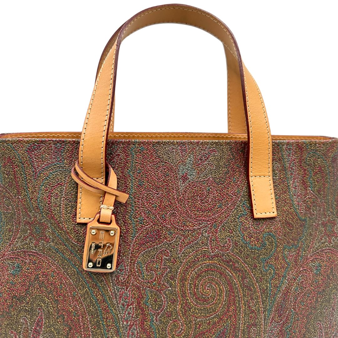 Manici di una borsa Etro in canvas trama paisley in varie tonalità calde e parti in pelle beige, dettagli metallici dorati, munita di doppi manici. Indossabile a mano. Completa di dustbag e charm decorativo amovibile.