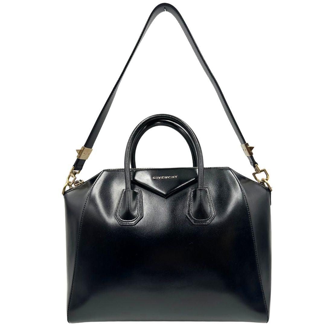 Front di una borsa Givenchy Antigona in pelle nera munita di doppi manici stondati, parti metalliche dorate e una tracolla non amovibile e non regolabile.