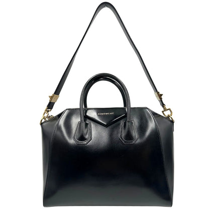Front di una borsa Givenchy Antigona in pelle nera munita di doppi manici stondati, parti metalliche dorate e una tracolla non amovibile e non regolabile.