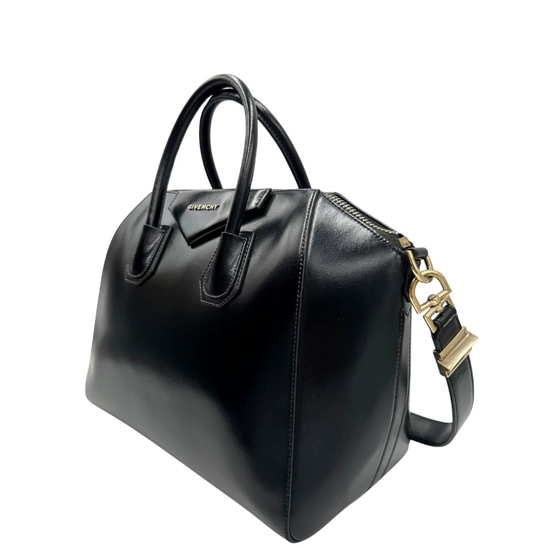 Laterale destro di una borsa Givenchy Antigona in pelle nera munita di doppi manici stondati, parti metalliche dorate e una tracolla non amovibile e non regolabile.