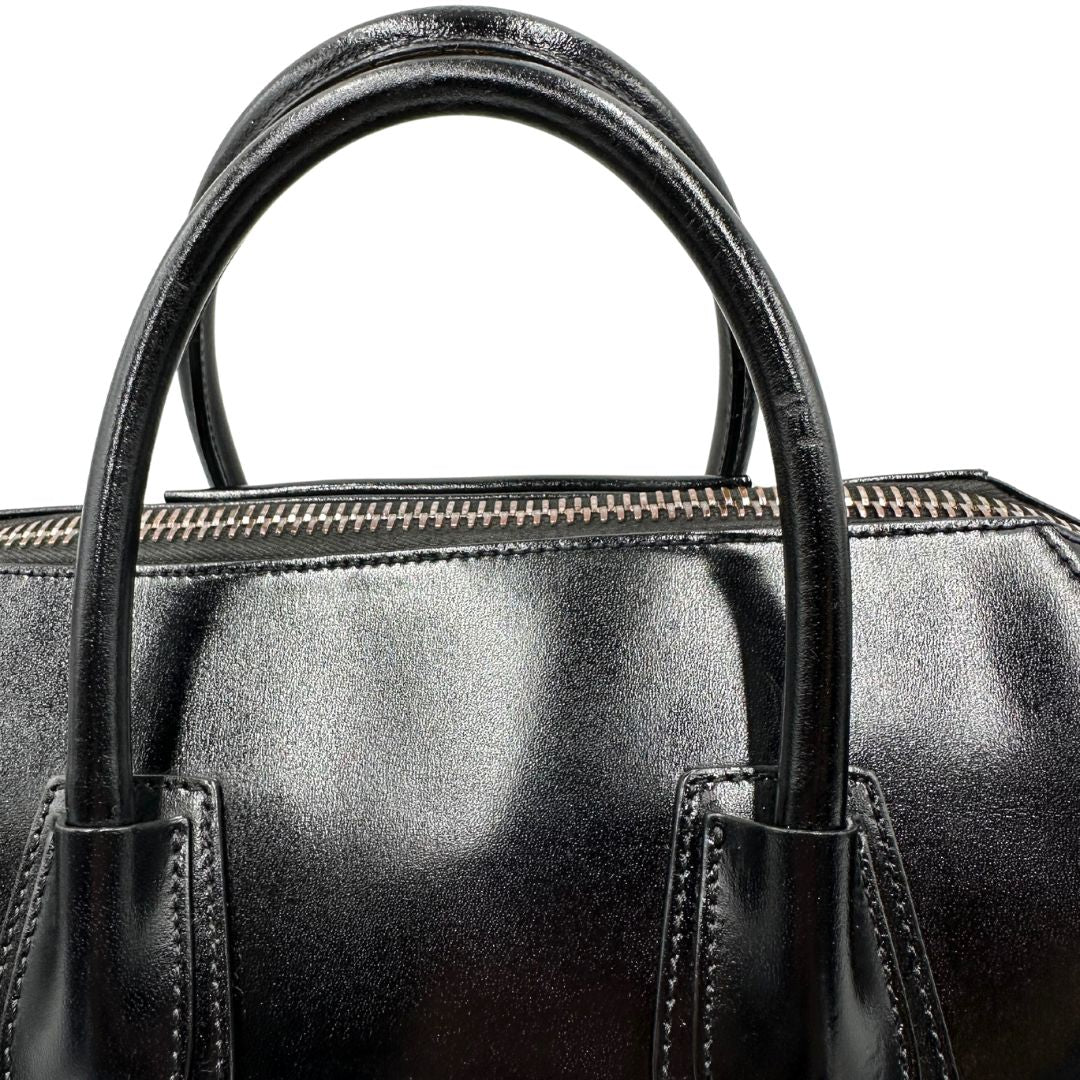 Manici di una borsa Givenchy Antigona in pelle nera munita di doppi manici stondati, parti metalliche dorate e una tracolla non amovibile e non regolabile.