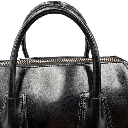 Manici di una borsa Givenchy Antigona in pelle nera munita di doppi manici stondati, parti metalliche dorate e una tracolla non amovibile e non regolabile.