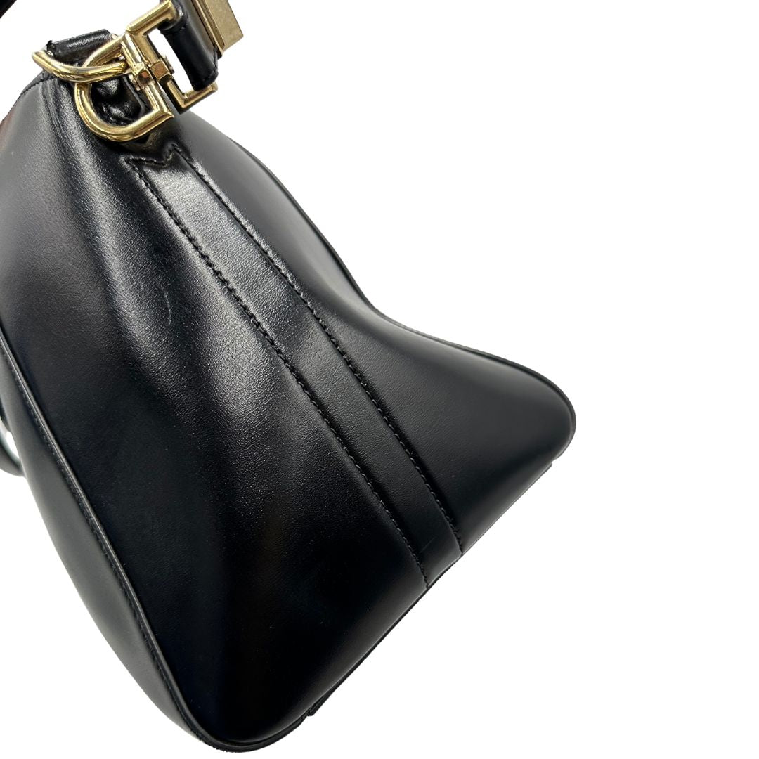Vista laterale di una borsa Givenchy Antigona in pelle nera munita di doppi manici stondati, parti metalliche dorate e una tracolla non amovibile e non regolabile.
