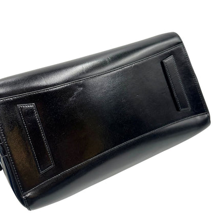 Base di una borsa Givenchy Antigona in pelle nera munita di doppi manici stondati, parti metalliche dorate e una tracolla non amovibile e non regolabile.