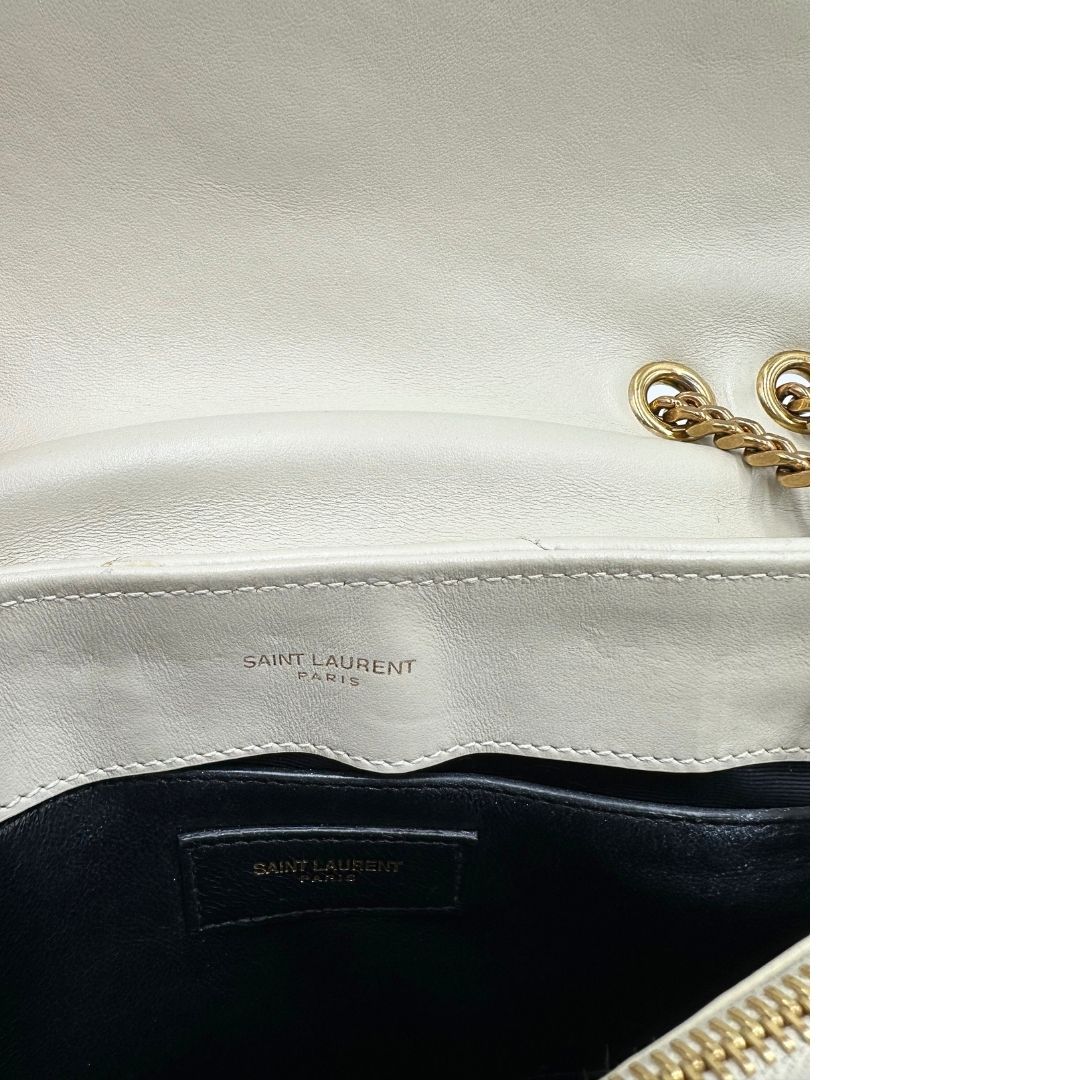 Interno di una borsa Saint Laurent in pelle trapuntata bianco latte con tracolla scorrevole in catena e spallacci in pelle, con parti metalliche dorate e iconico logo Cassandre sul front. Completa di dustbag. Indossabile a spalla o a tracolla.