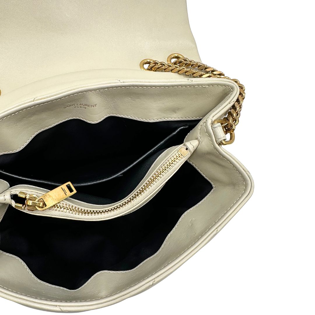 Interno di una borsa Saint Laurent in pelle trapuntata bianco latte con tracolla scorrevole in catena e spallacci in pelle, con parti metalliche dorate e iconico logo Cassandre sul front. Completa di dustbag. Indossabile a spalla o a tracolla.