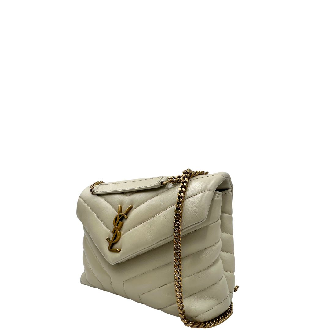 Laterale destro di una borsa Saint Laurent in pelle trapuntata bianco latte con tracolla scorrevole in catena e spallacci in pelle, con parti metalliche dorate e iconico logo Cassandre sul front. Completa di dustbag. Indossabile a spalla o a tracolla.