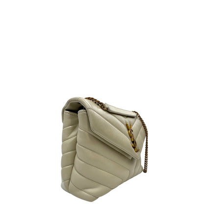 Laterale sinistro di una borsa Saint Laurent in pelle trapuntata bianco latte con tracolla scorrevole in catena e spallacci in pelle, con parti metalliche dorate e iconico logo Cassandre sul front. Completa di dustbag. Indossabile a spalla o a tracolla.