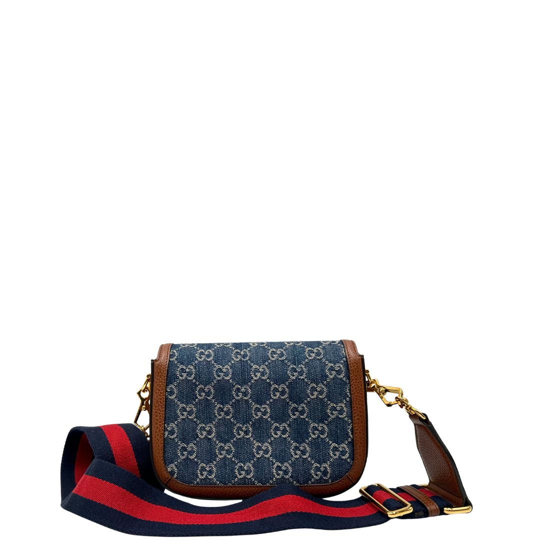 Retro di una borsa Gucci in tessuto effetto denim con trama GG , finiture in pelle marroni e parti metalliche dorate; munita di una tracolla Web in tessuto blu e rossa e una tracolla in pelle, entrambe amovibili e regolabili. Completa di dustbag.