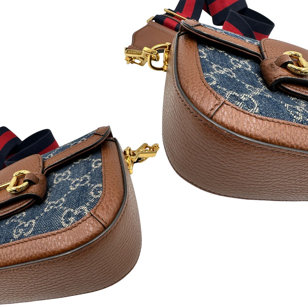 Angoli di una borsa Gucci in tessuto effetto denim con trama GG , finiture in pelle marroni e parti metalliche dorate; munita di una tracolla Web in tessuto blu e rossa e una tracolla in pelle, entrambe amovibili e regolabili. Completa di dustbag.