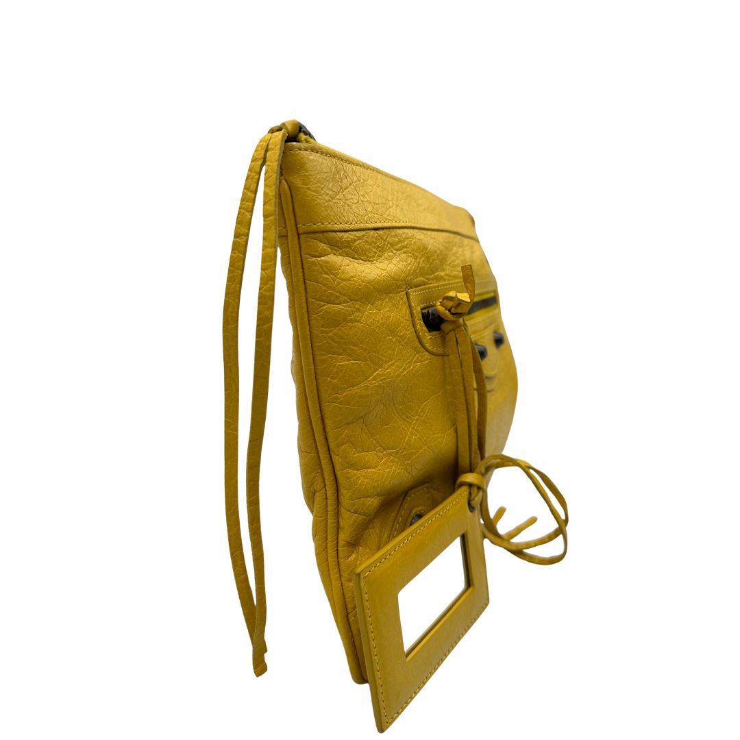 lato  Pochette Balenciaga in pelle effetto invecchiato gialla con metalleria color bronzo anticato scuro; munita di un polsino amovibile, da portare a mano, di lusso, originale, ottime condizioni, usata. 