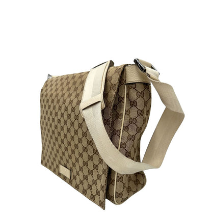 Laterale destro di una borsa Gucci in tessuto beige GG , von finiture in pelle bianco avorio con parti metalliche argentate. Munita di tracolla regolabile e non amovibile, in tessuto con spallaccio in pelle. Completa di dustbag. Indossabile a tracolla.