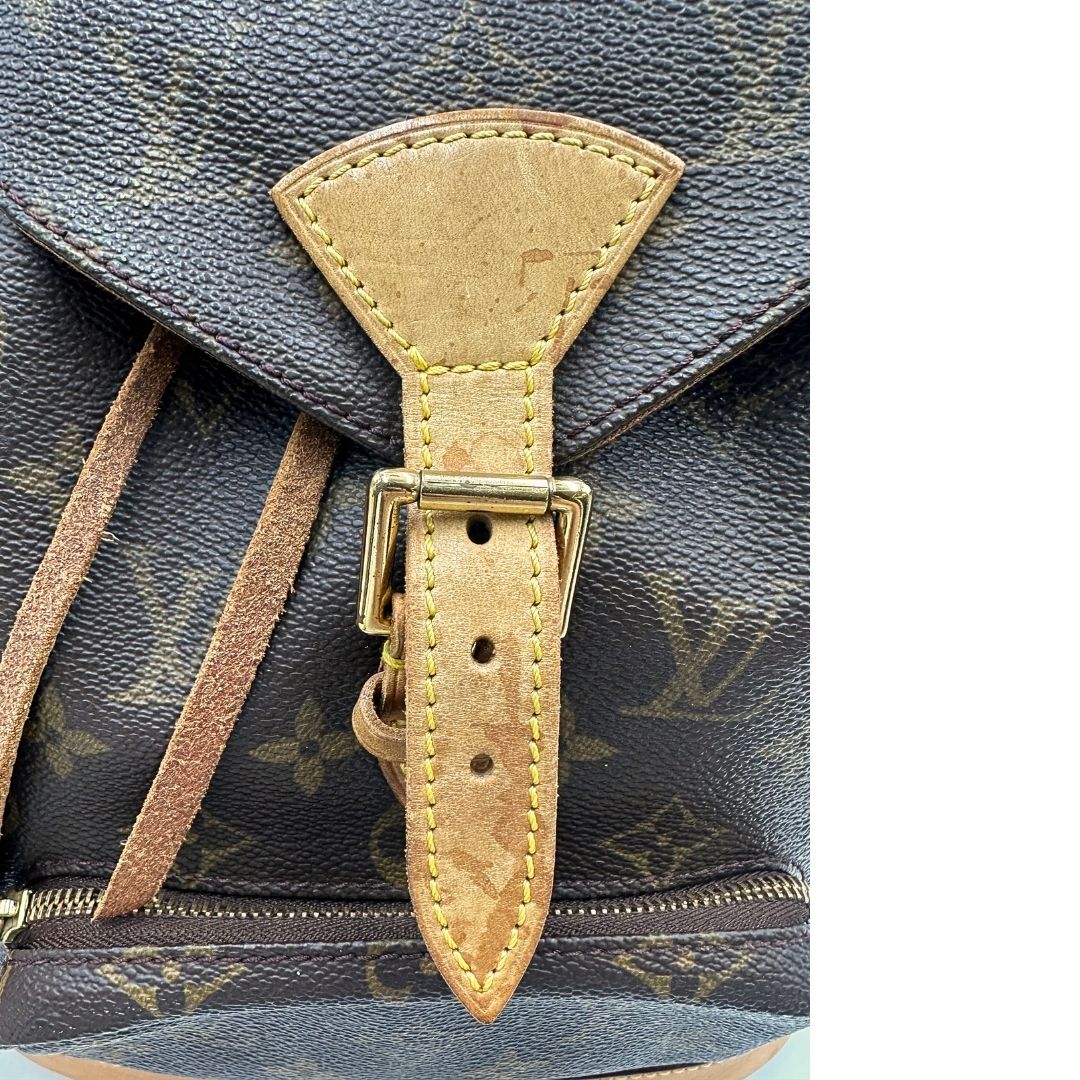 Chiusura di uno zaino Montsouris mini in canvas marrone monogram con finiture in vacchetta naturale e parti metalliche dorate, munito di un anello sulla parte superiore e due bretelle in vacchetta regolabili con fibbie. Completo di dustbag.