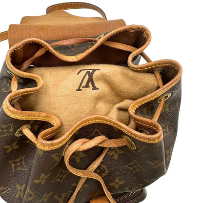 Chiusura di uno zaino Montsouris mini in canvas marrone monogram con finiture in vacchetta naturale e parti metalliche dorate, munito di un anello sulla parte superiore e due bretelle in vacchetta regolabili con fibbie. Completo di dustbag.